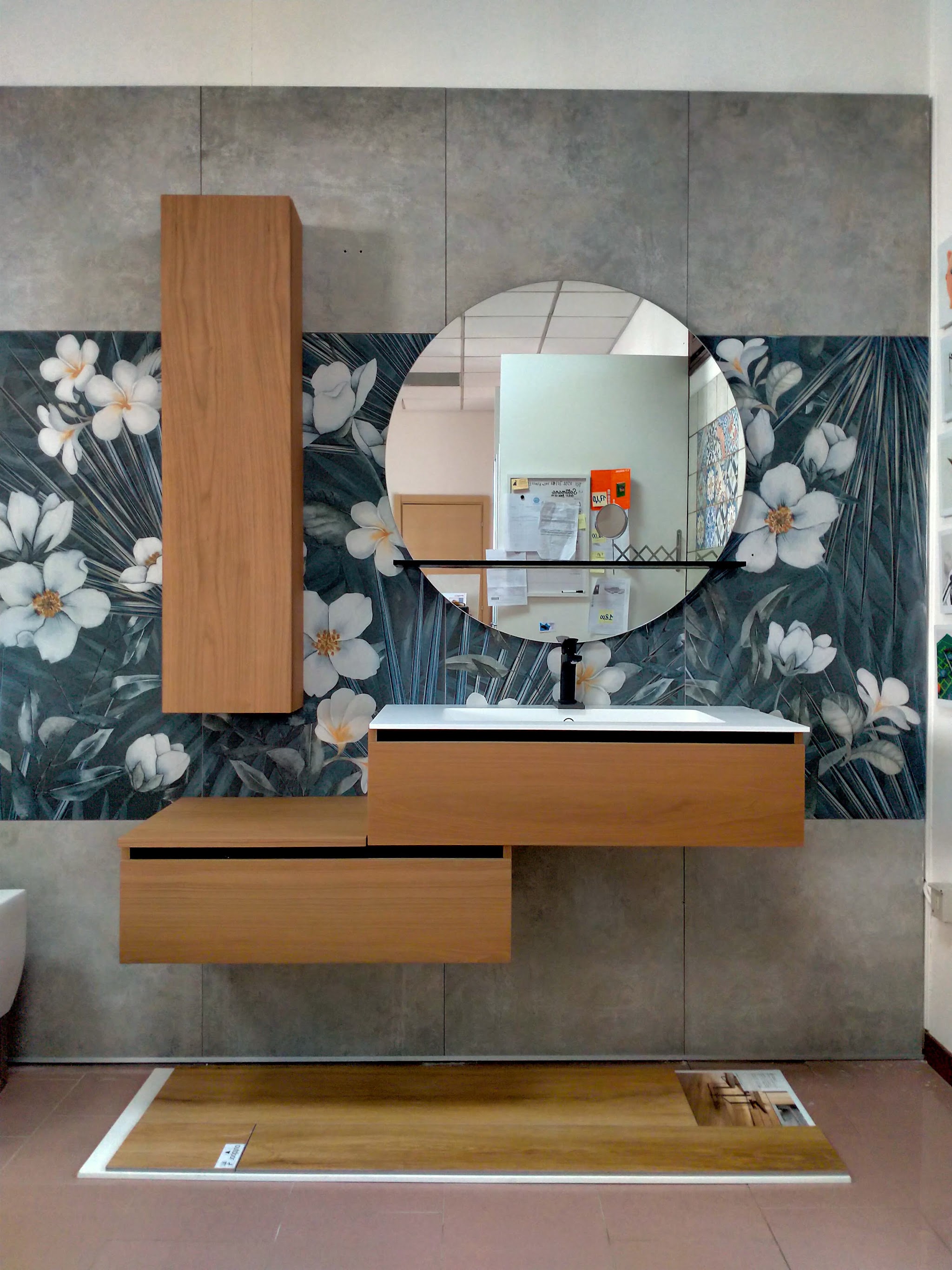 Composizione bagno con mobile in legno, specchio tondo e rivestimento floreale